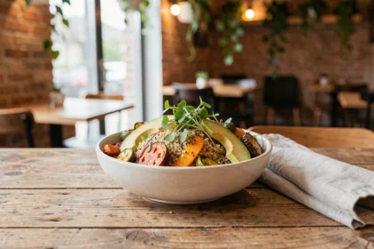 Bol de repas healthy coloré servi dans un restaurant bistronomique de Loire-Atlantique, avec quinoa, légumes rôtis et avocat sur table en bois rustique